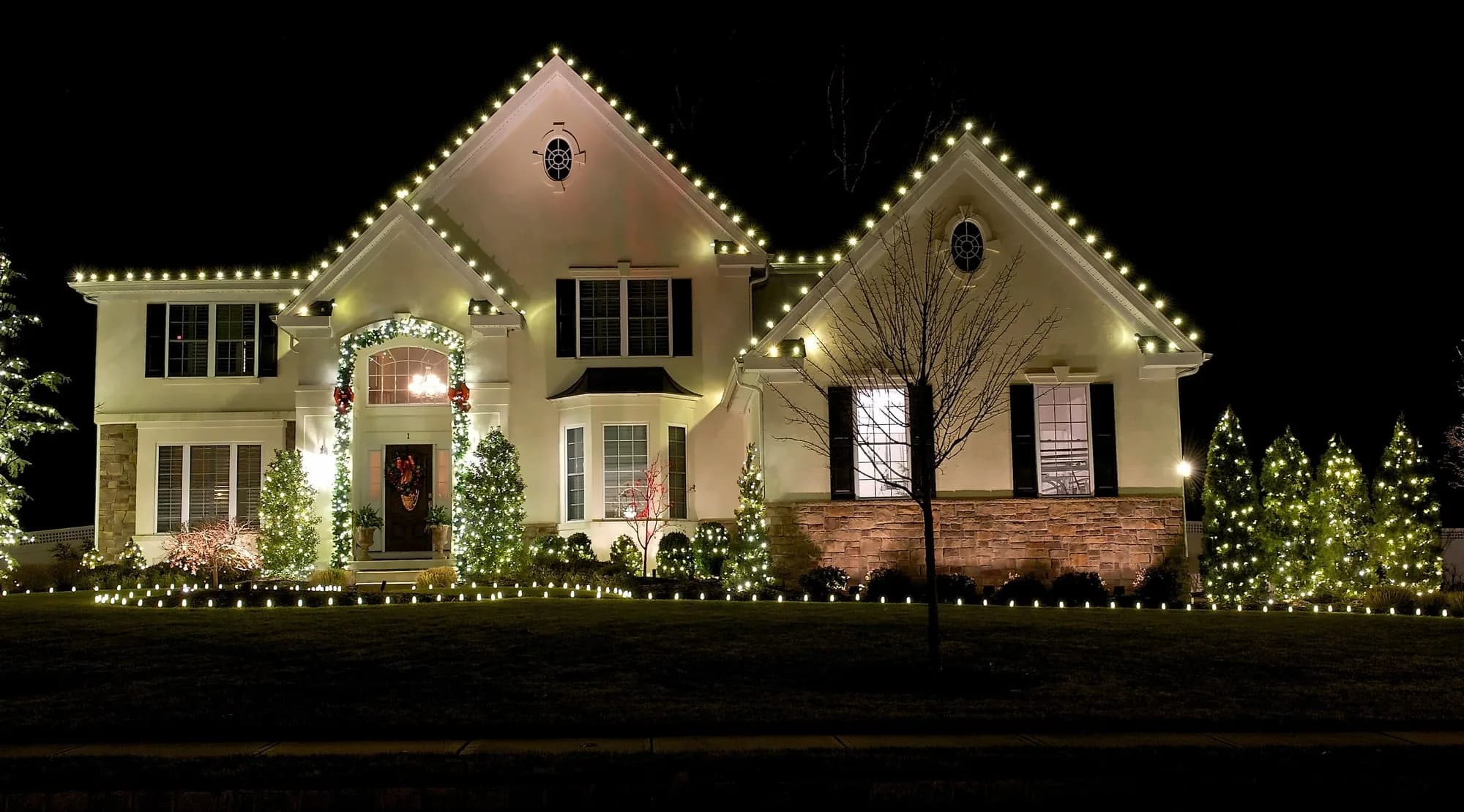 Custom white Christmas roofline lights on a home at night, from the OCF photo collection